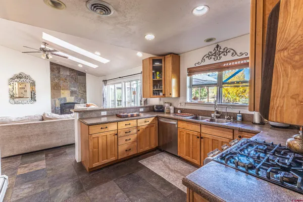 a large kitchen with stainless steel appliances granite countertop a sink and wooden cabinets