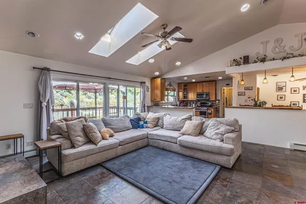 a living room with furniture kitchen view and a large window
