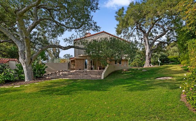 a view of a brick house with a big yard and large trees