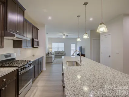 a kitchen with stainless steel appliances granite countertop a stove a sink a oven a dining table and chairs