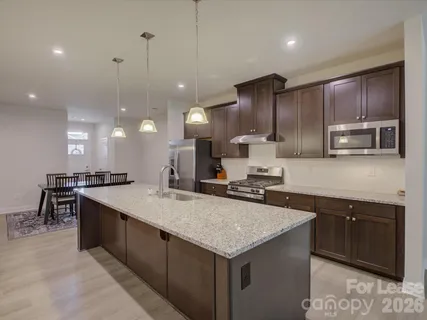 a kitchen with kitchen island granite countertop a sink counter top space appliances and cabinets