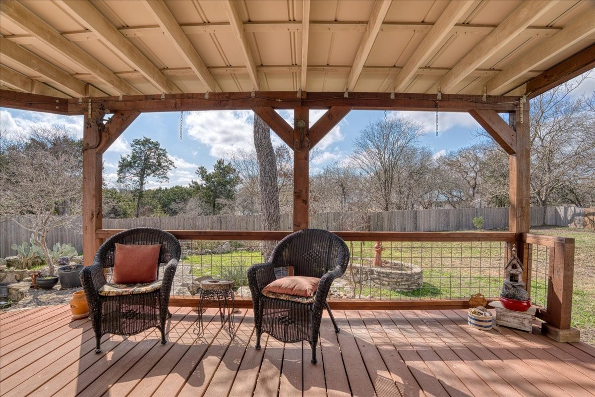 20 Saddle Rock Ridge Street Wimberley, TX 78676 - Photo 29 of 40 a patio with wooden floor a yard a table and chairs