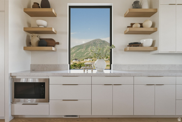 923 North Emery Lane Elk Ridge, UT 84651 - Photo 19 of 101 Modern kitchen cabinetry featuring a built-in microwave, light-toned countertops, and floating wood shelves