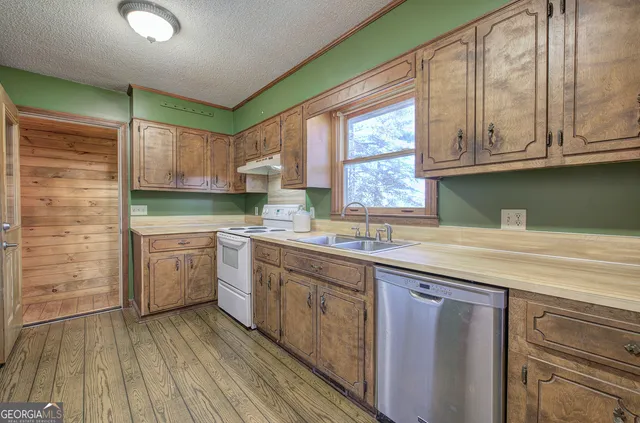 a kitchen with granite countertop wooden cabinets a sink a window and stainless steel appliances