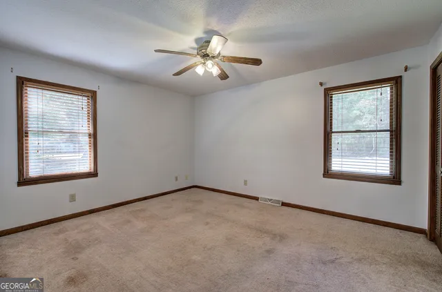 an empty room with windows and fan