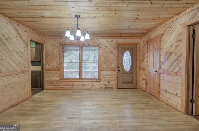 a view of a hallway with wooden floor and chandelier