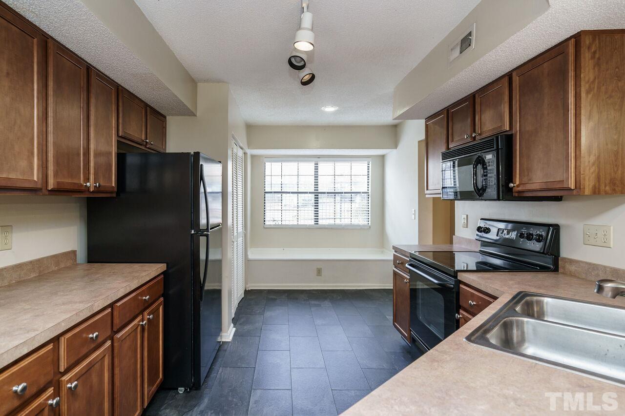 7906 Falcon Rest Circle Raleigh, NC 27615 - Photo 7 of 20 a kitchen with granite countertop stainless steel appliances a sink dishwasher stove top oven and wooden cabinets