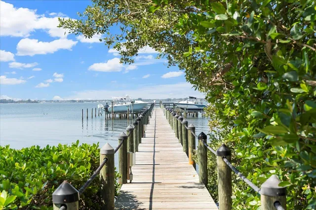 a view of a white house next to a yard and palm trees