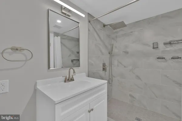 a bathroom with a sink shower and a mirror