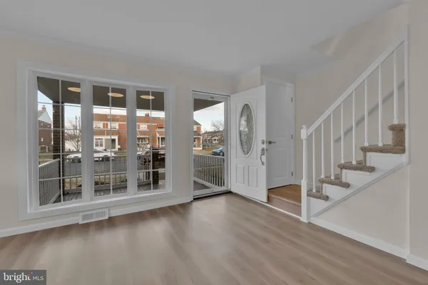 a view of front door with hallway and wooden floor