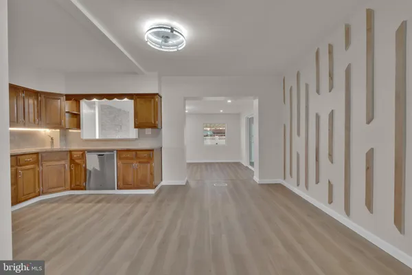 a view of a hallway with wooden floor and a kitchen