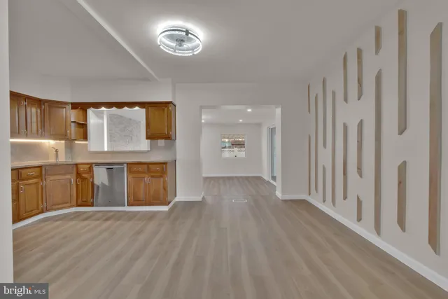 a view of a hallway with wooden floor and a kitchen
