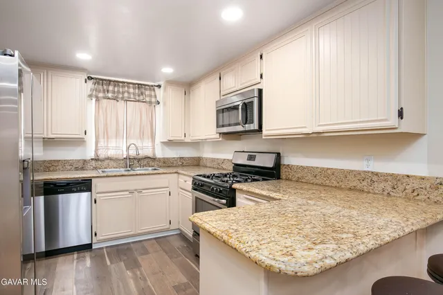 a kitchen with stainless steel appliances granite countertop a stove a sink and a microwave