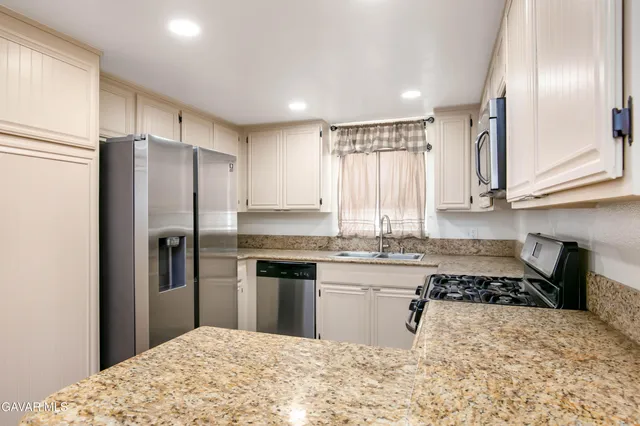 a kitchen with stainless steel appliances granite countertop a refrigerator stove and sink