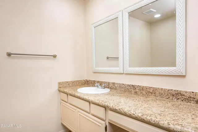 a bathroom with a granite countertop sink and a mirror