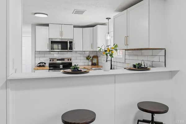 a kitchen with stainless steel appliances a sink a stove a microwave a refrigerator a cabinets and wooden floor