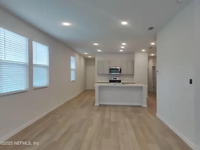 a view of kitchen with kitchen island stainless steel appliances wooden cabinets and window