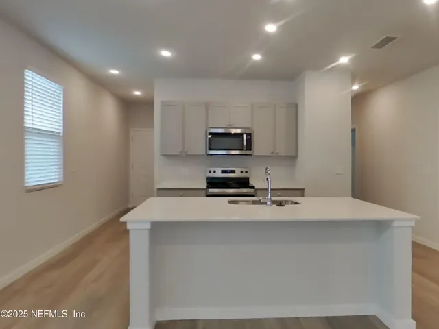 a kitchen with kitchen island a sink stainless steel appliances and cabinets