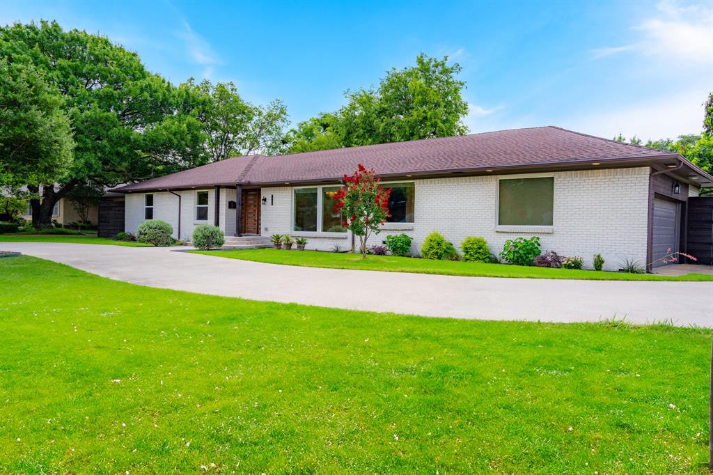 5710 Forest Lane Dallas, TX 75230 - Photo 1 of 1 a front view of a house with a garden and yard