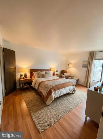 a spacious bedroom with a bed a couch and a flat tv screen on a dresser