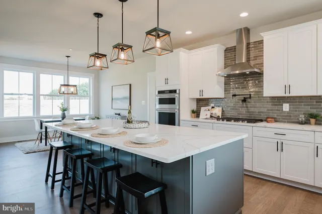 a large kitchen with kitchen island a stove a sink a center island a dining table and chairs