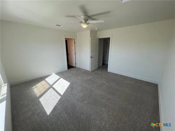 an empty room with windows and ceiling fan