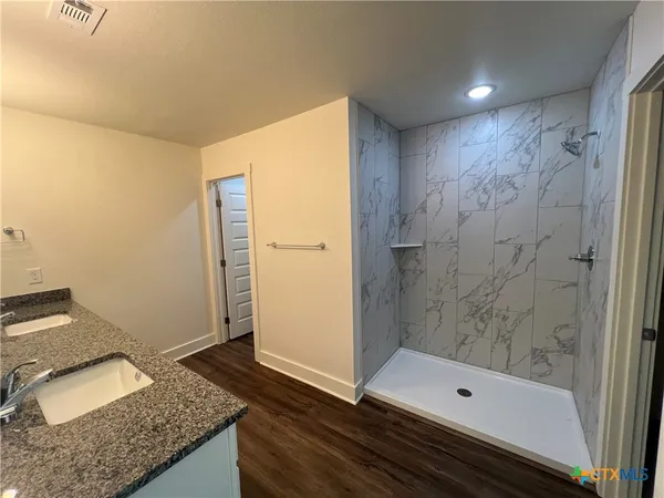 a bathroom with a granite countertop sink and shower