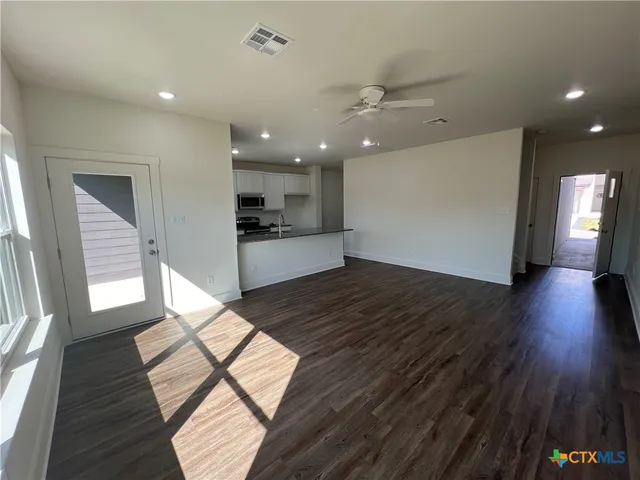 a view of a living room with wooden floor and a kitchen