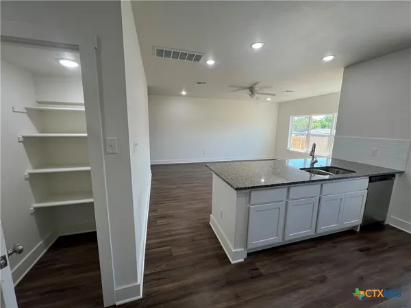 a kitchen with granite countertop a sink and a wooden floor
