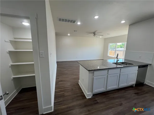 a kitchen with granite countertop a sink and a wooden floor