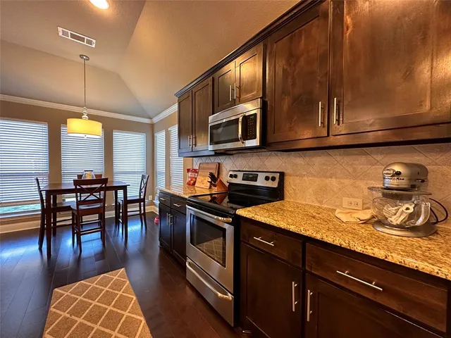 a kitchen with stainless steel appliances granite countertop wooden cabinets a stove top oven a sink and dishwasher