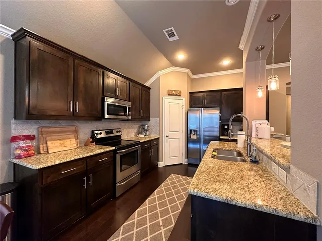 a kitchen with stainless steel appliances granite countertop wooden cabinets a stove top oven a sink and dishwasher
