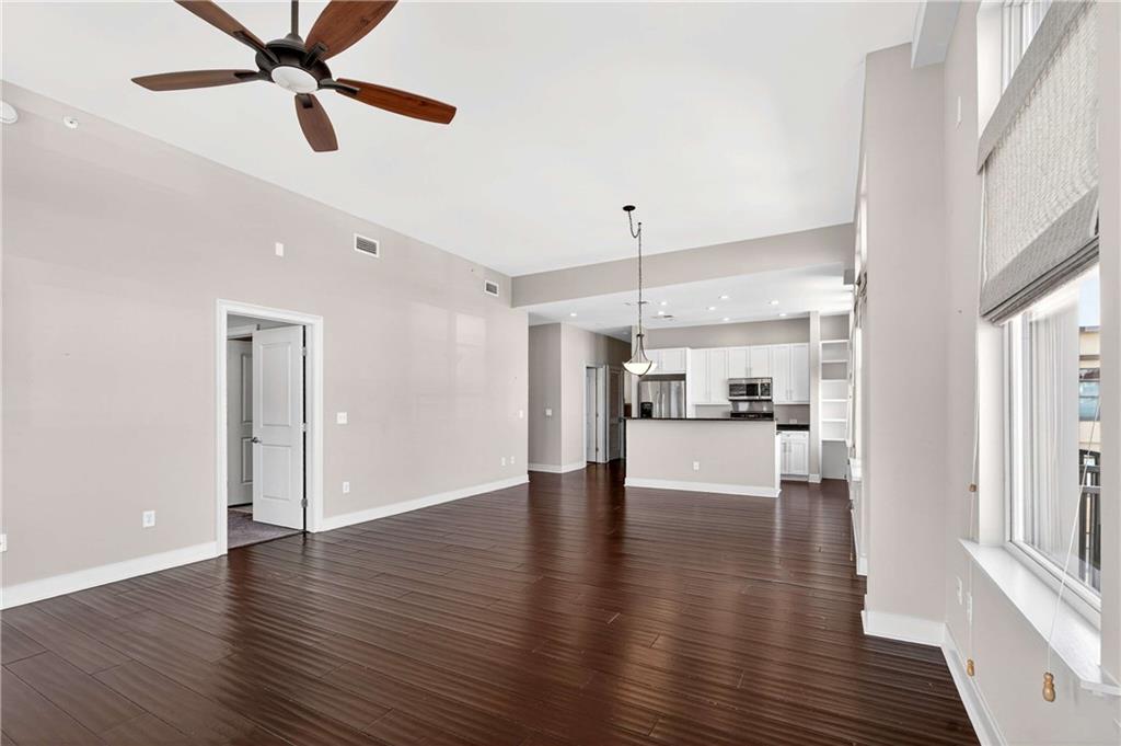 201 West Ponce De Leon Avenue, Unit 702 Decatur, GA 30030 - Photo 10 of 41 a view of an empty room and kitchen with wooden floor and a ceiling fan