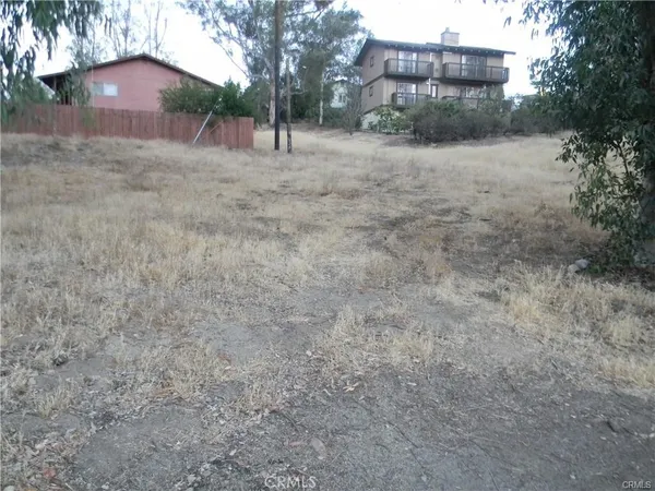 a view of a dry yard with wooden fence