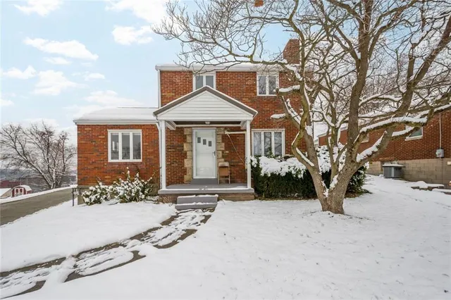 a front view of a house with a yard covered in snow