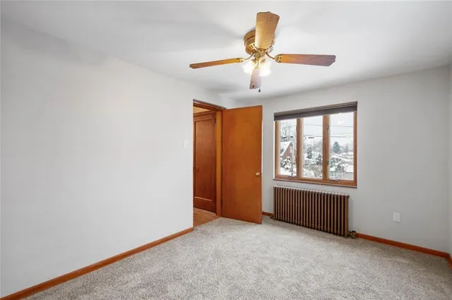 an empty room with chandelier fan and windows