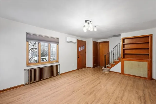 an empty room with wooden floor closet and windows