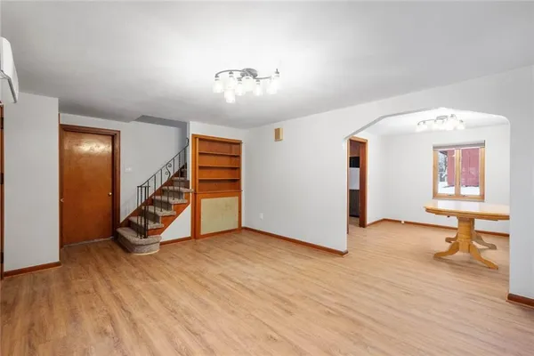 a view of an empty room with stairs and a wooden floor