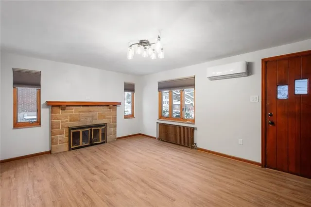 an empty room with wooden floor fireplace and windows
