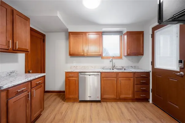 a kitchen with stainless steel appliances granite countertop wooden cabinets a sink and dishwasher a stove with wooden floors