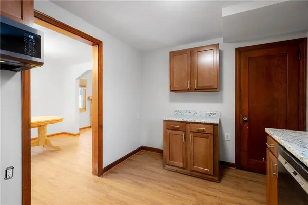 a view of a hallway with wooden floor and a kitchen