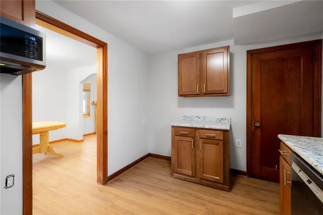 a view of a hallway with wooden floor and a kitchen