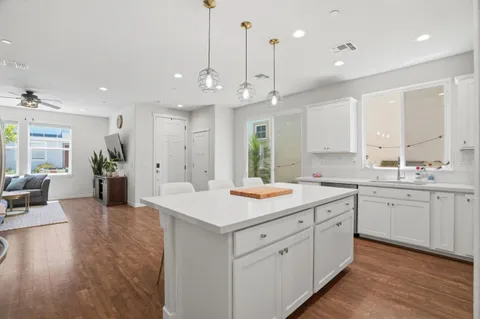 a hall with kitchen island white cabinets and stainless steel appliances