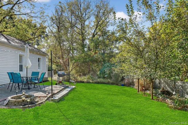 a view of a backyard with table and chairs potted plants and large tree