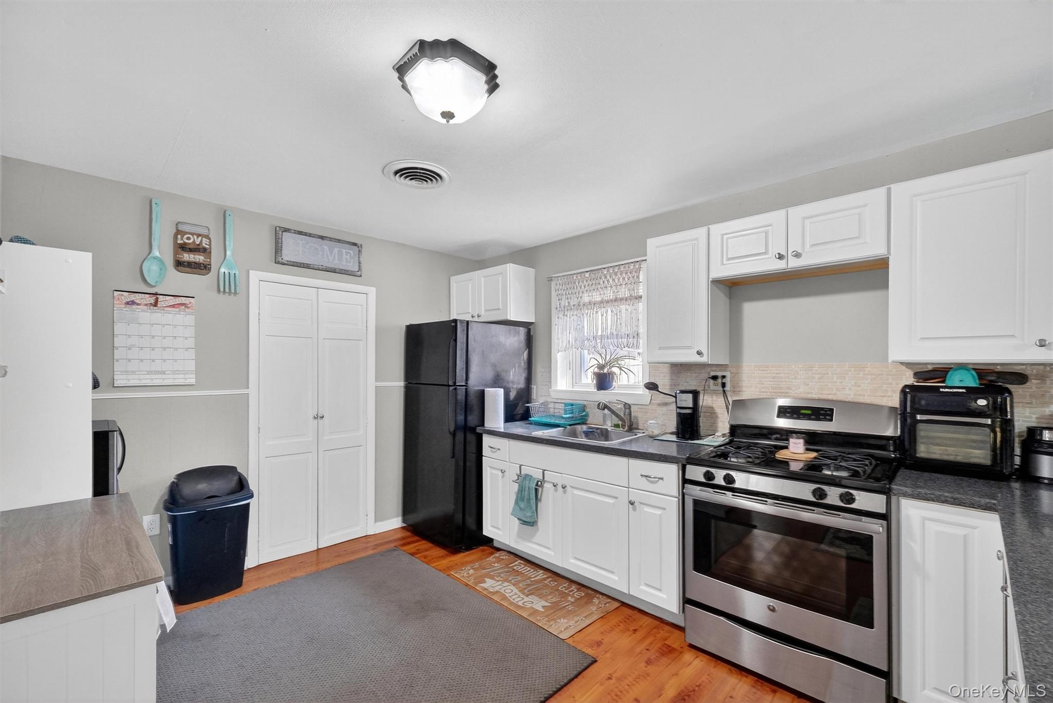 27 Peckham Road Poughkeepsie, NY 12603 - Photo 10 of 27 a kitchen with stainless steel appliances a stove a refrigerator a sink a stove and white cabinets with wooden floor