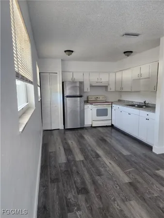 a kitchen with cabinets wooden floor and stainless steel appliances