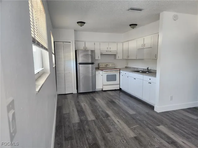 a kitchen with a refrigerator a sink and wooden floor