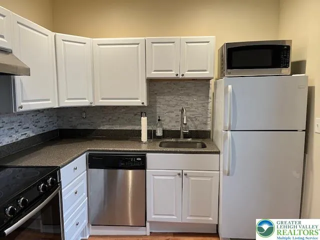 a white refrigerator freezer and a stove sitting inside of a kitchen