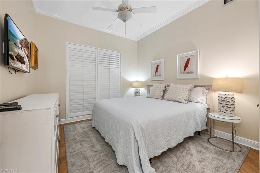 705 10th Street South, Unit 202 Naples, FL 34102 - Photo 9 of 17 a bedroom with a bed and a chandelier