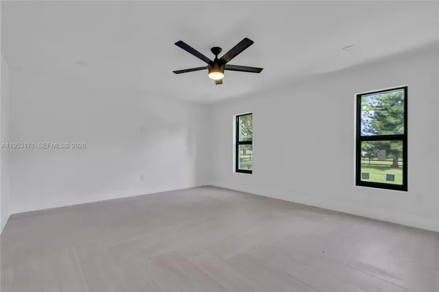 an empty room with windows and a ceiling fan
